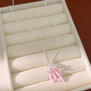 Dettaglio di collana con fiocco rosa e fiori di zircone su vassoio di velluto.