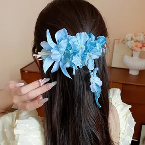 Close-up of blue fabric flower hair clip with pearls and tassels on dark hair