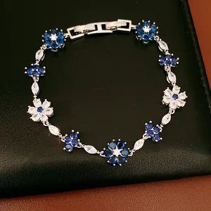 Detailed view of a silver-tone bracelet with blue and clear zircon flower motifs.
