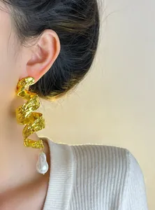 Close-up detail of vintage gold spiral earrings with white baroque pearl drop pendant