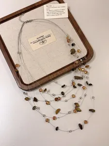 Primo piano di collana multistrato con perle marroni irregolari e accenti d'argento