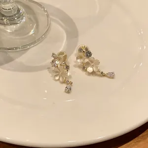 Elegant French style floral earrings with zirconia drops on a white ceramic plate.
