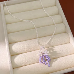 Dettaglio di collana con ciondolo a fiocco viola e fiori di zircone in un vassoio