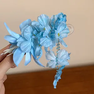 Detailed view of blue fabric flower hair clip with tassel and butterfly