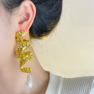Detailed view of vintage gold spiral earrings with baroque pearl on an Asian model.