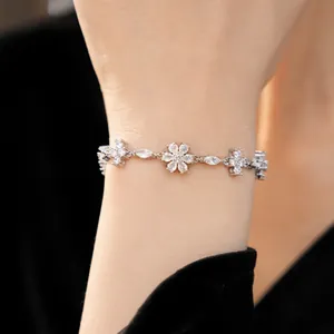 Close-up of elegant vintage silver bracelet with sparkling zircon flower and cross charms