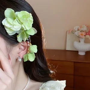 Detailed view of a green fabric flower hair clip with pearl tassels on long dark hair
