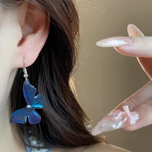 Detailed close-up of elegant blue resin butterfly clip-on earrings worn on a model's ear
