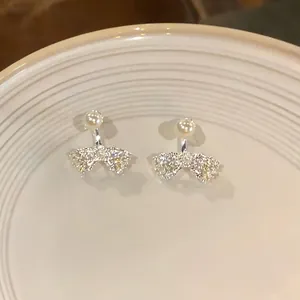 Close-up of elegant French bow earrings with white pearl and sparkling crystals.