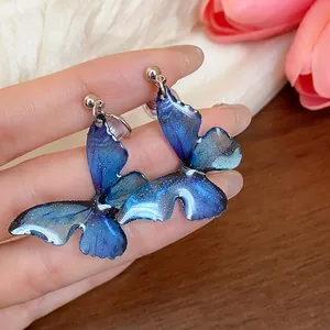 Close-up detail of blue gradient resin butterfly wing earrings with glitter