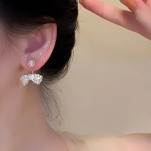 Close-up detail of a French style bow pearl earring worn on an ear, sparkling design