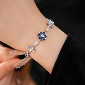 Close-up of floral and cross pattern bracelet with blue and clear zircon stones.