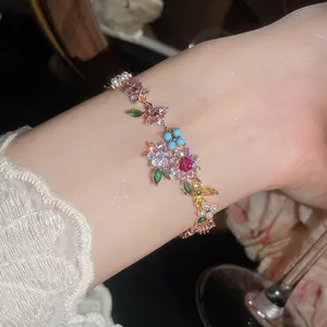 Detalle de una pulsera bañada en oro de 18k con flores de circonio de colores