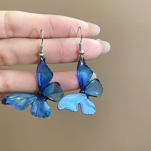 Detailed close-up view of elegant blue resin butterfly wing earrings with subtle glitter