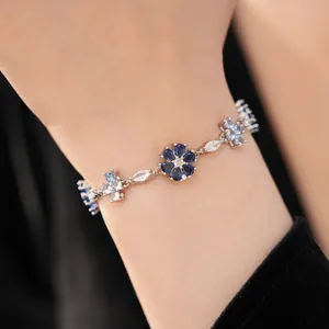 Detailed close-up of a vintage style flower and cross zircon inlaid silver-tone link bracelet