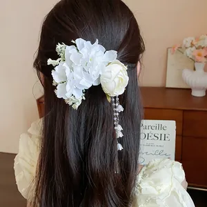 Detailed back view of a white fabric flower hair clip with pearl tassels on long hair