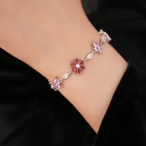 Close-up of a vintage-style silver bracelet with pink and red zircon flowers on a wrist