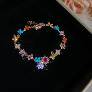 Vista macro de una pulsera bañada en oro 18k con flores y mariposas de circón de colores