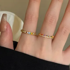 Detailed close-up showing two ultra-thin gold rings with vibrant rainbow stones.