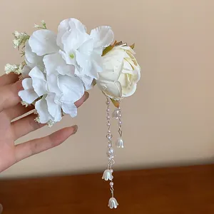 Close-up of an elegant white fabric floral hair clip featuring pearl tassels and bell charms