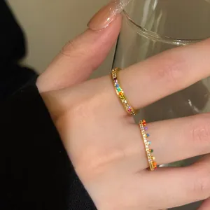Detailed view of two slim gold rings with colorful rainbow zircons for stacking style