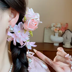Close-up of pink fabric flower hair clip with elegant pearl tassel on model's braid