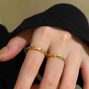 Close-up of gold-plated stacked rings featuring colorful rainbow zircons on finger