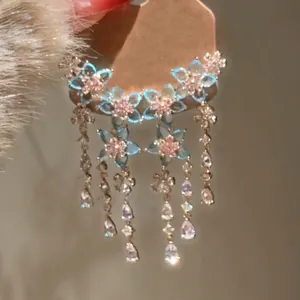 Dettaglio di lussuosi orecchini a nappa con cristalli a fiori blu e strass a goccia