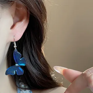 Close-up of blue butterfly resin earring with glitter on an elegant model's ear
