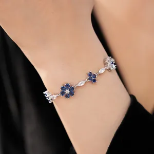 Close-up detail showing flower and cross motifs on a vintage blue zirconia link bracelet.