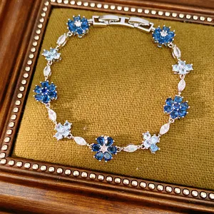 Macro view of a vintage floral zircon bracelet featuring blue and white stones on velvet.