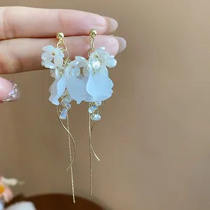 Close-up detail of elegant French style white floral tassel earrings with gold chains