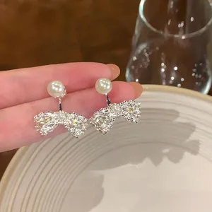 Detailed view of French bow pearl earrings with sparkly crystals and silver-tone finish