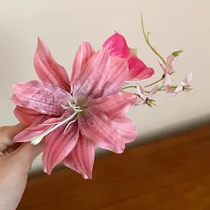 A hand holding a detailed pink fabric lily flower hair clip for elegant vacation styling.
