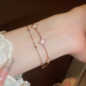 Primer plano de una pulsera de doble capa bañada en oro de 18k con elegantes tréboles de suerte.