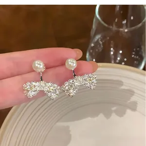 Detailed macro view of elegant French bow pearl stud earrings with sparkling crystal accents
