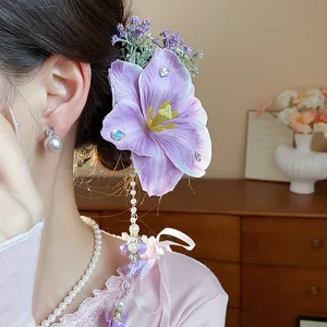 Detailed close-up of elegant purple fabric flower hair clip with dangling pearl tassel