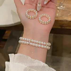 Close-up of elegant double-layer pearl bracelet and matching rings on wrist