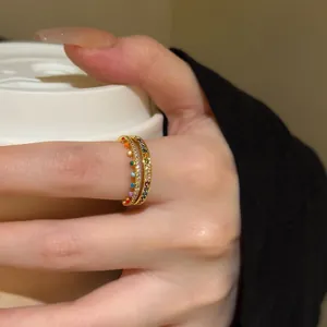 Close-up macro view of a delicate gold-tone ring set with colorful rainbow zircons.