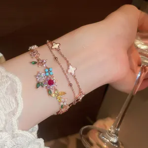 Primer plano detallado de pulseras de flores y tréboles chapadas en oro de 18k y circonitas