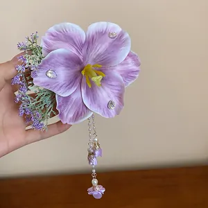 Detailed view of a handmade purple fabric flower hair clip with pearl tassels.