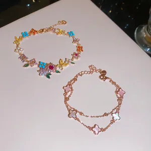 Detalle que muestra dos pulseras de oro rosa con circonitas y colgantes de trébol