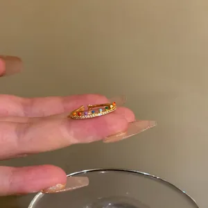 Detailed close-up view of the rainbow zircon gold ring on a finger with manicured nails.