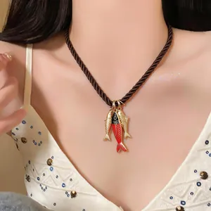Close-up of lightweight luxury oil drip fish pendant necklace worn on a model's collarbone