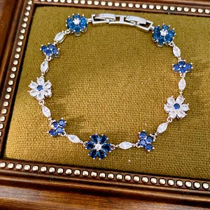 Detailed view of a vintage blue zircon flower and cross bracelet on green velvet display.