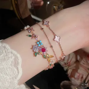 Primer plano de elegantes pulseras de oro rosa con flores de circón de colores.
