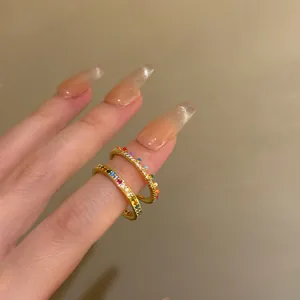 Detailed view of elegant gold-plated stacking rings with colorful rainbow zircon on a finger