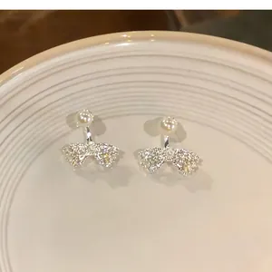 Detailed view of French style bow-knot earrings with shimmering pearls and zircons.