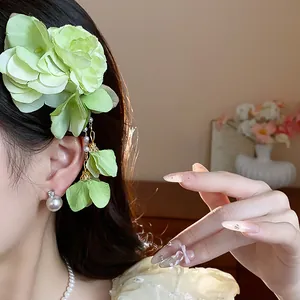 Close-up of light green fabric flower hair clip with pearl tassel on Asian model