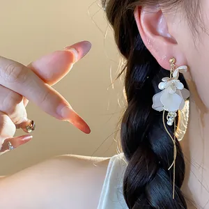 Close-up of elegant French floral tassel earrings featuring white petals and pearls.